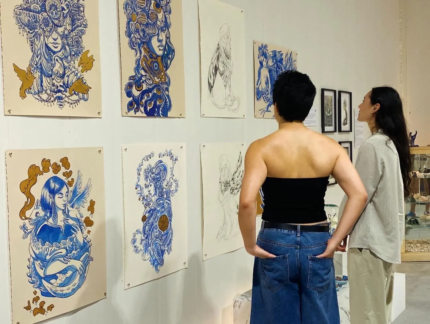 Two visitors in conversation in front of the hung works