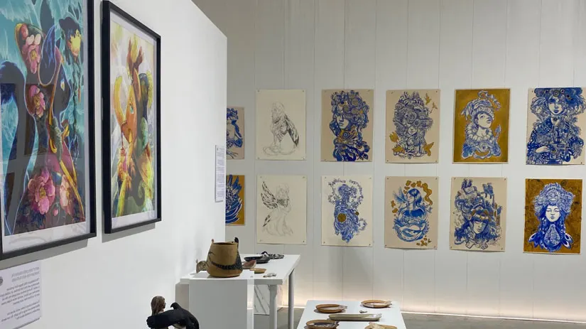 A hung wall of blue-and-gold works beside ceramics on plinths